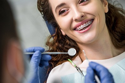 Girl with braces in the treatment chair smiling at her orthodontist