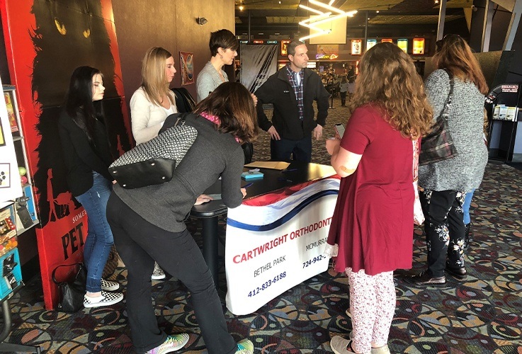 Team members at information table for community Involvement movie theater event