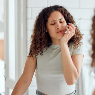 Woman experiencing pain while brushing her teeth