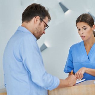 Man signing papers at dental office front desk