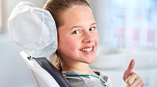 Girl in exam chair giving thumbs up