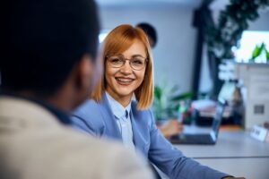 Woman in blue suit with red hair smiling with braces at work